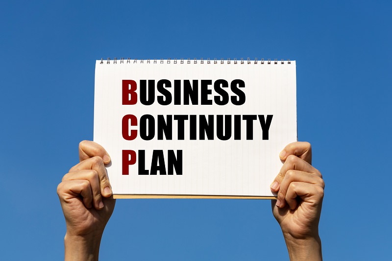 Business continuity plan text on notebook paper held by 2 hands